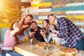 Cheerful young friends taking selfie with smart phone while sharing a pizza at bar restaurant Royalty Free Stock Photo